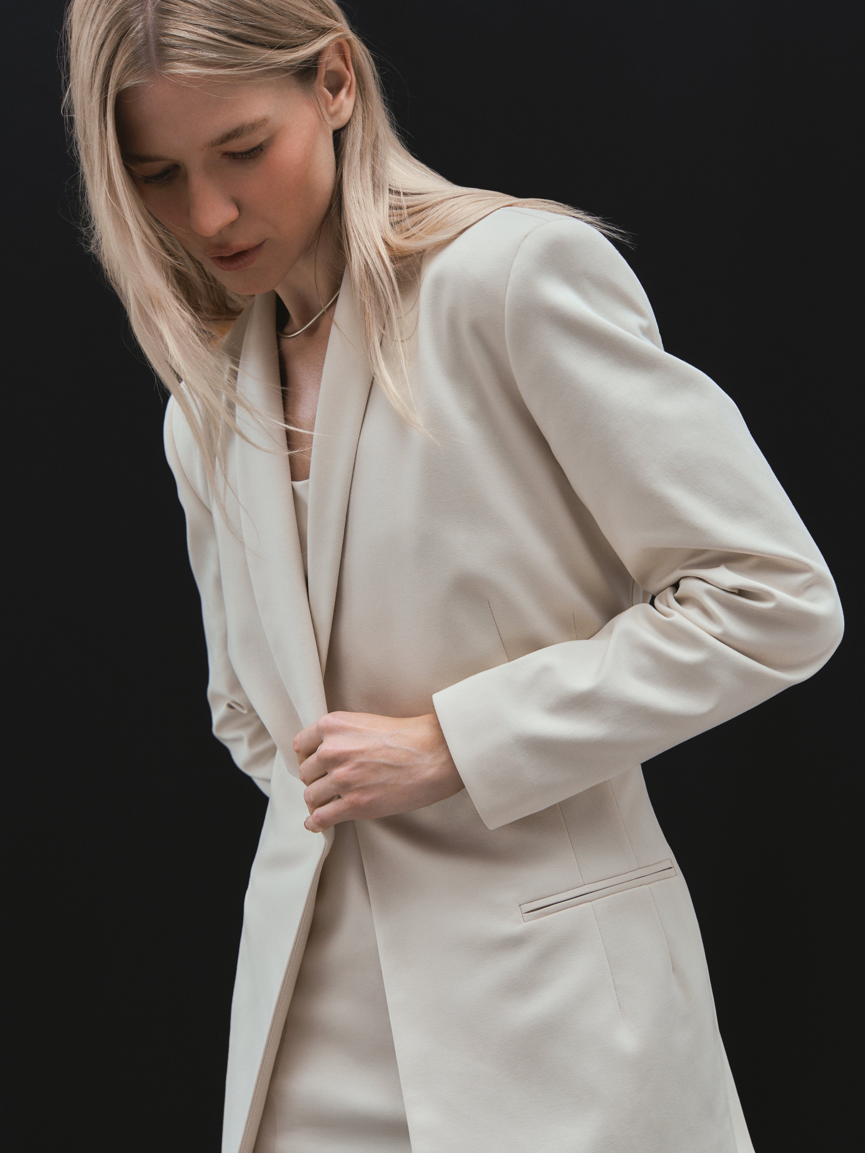 A model posing in a light beige organic cotton interlock blazer certified with GOTS