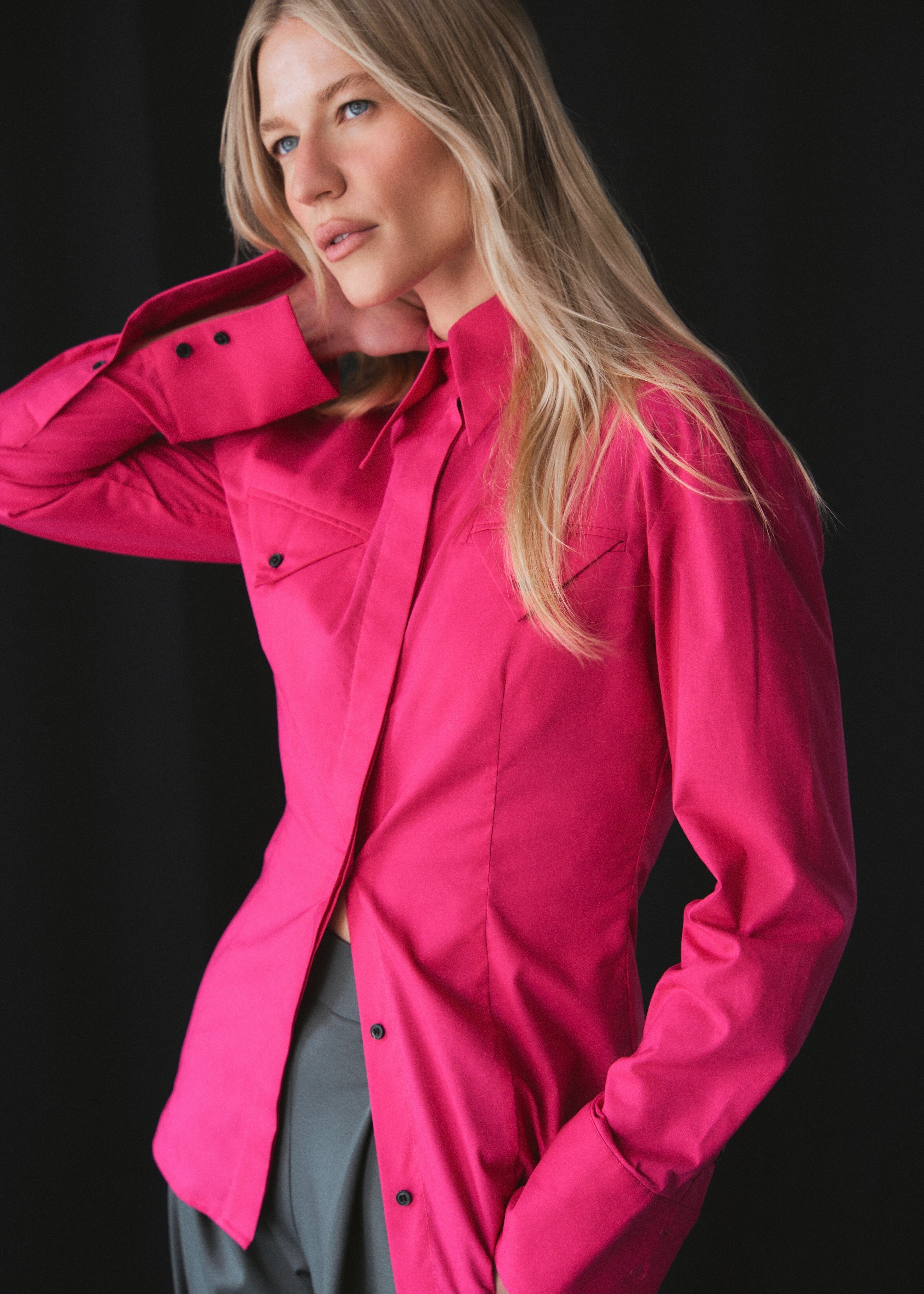 A model wearing a sustainable organic 100% cotton fitted shirt with pointed collar elongated silhouette and small black buttons