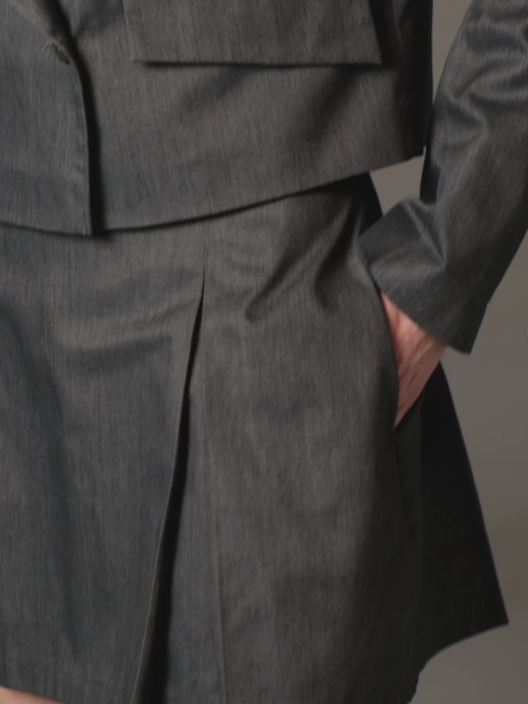 A model posing with slow movement wearing a sustainable set of jacket and skirt by HER CIPHER
