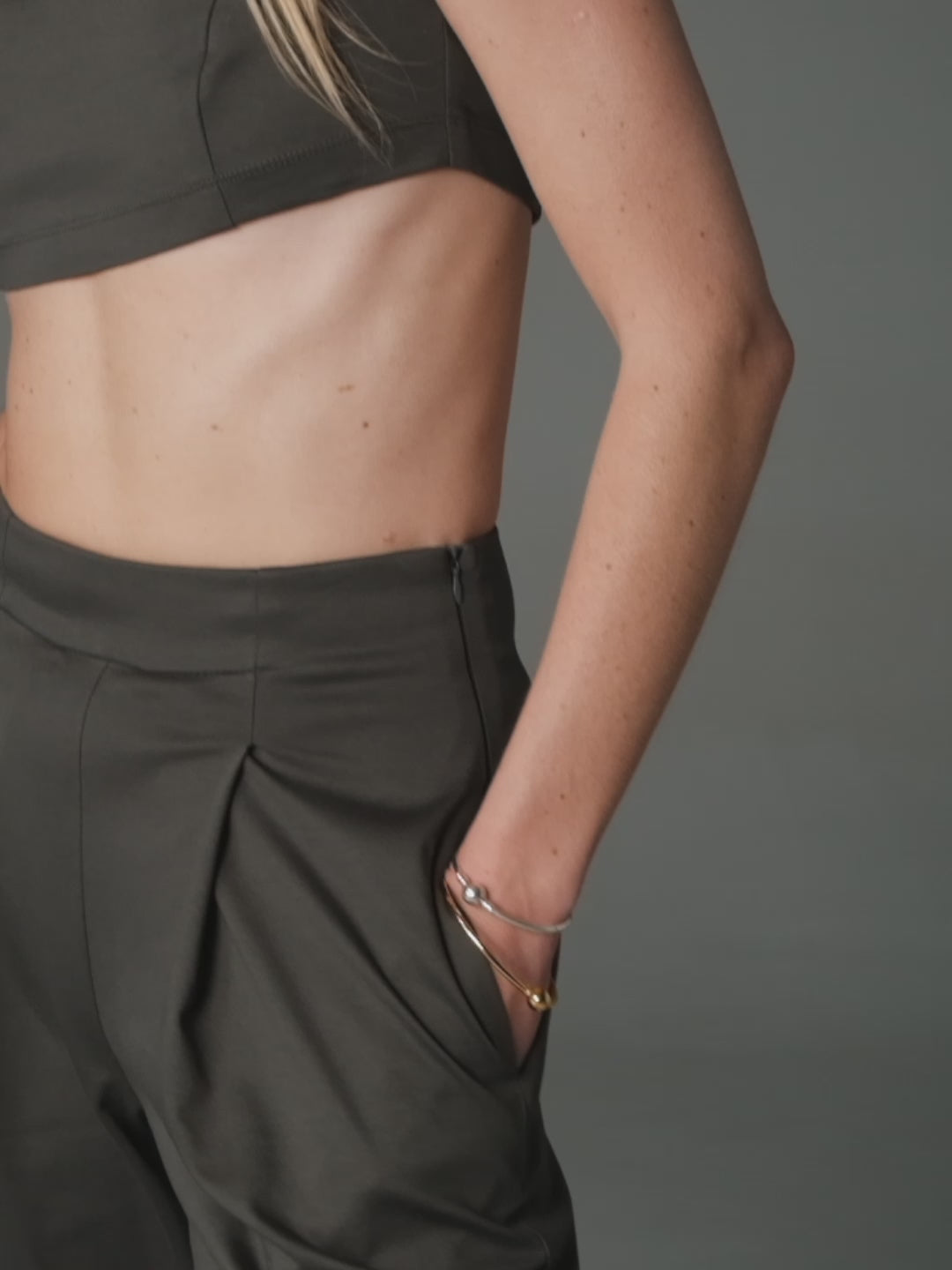 A model slowly posing wearing a grey fitted crop top and high waisted wide leg pants by HER CIPHER created from 100% organic cotton