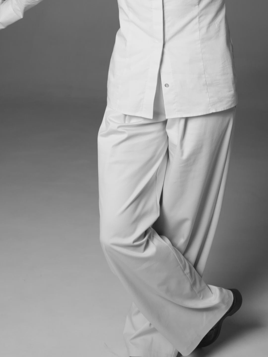 A model posing wearing a sustainable cotton shirt and pants in light beige color.